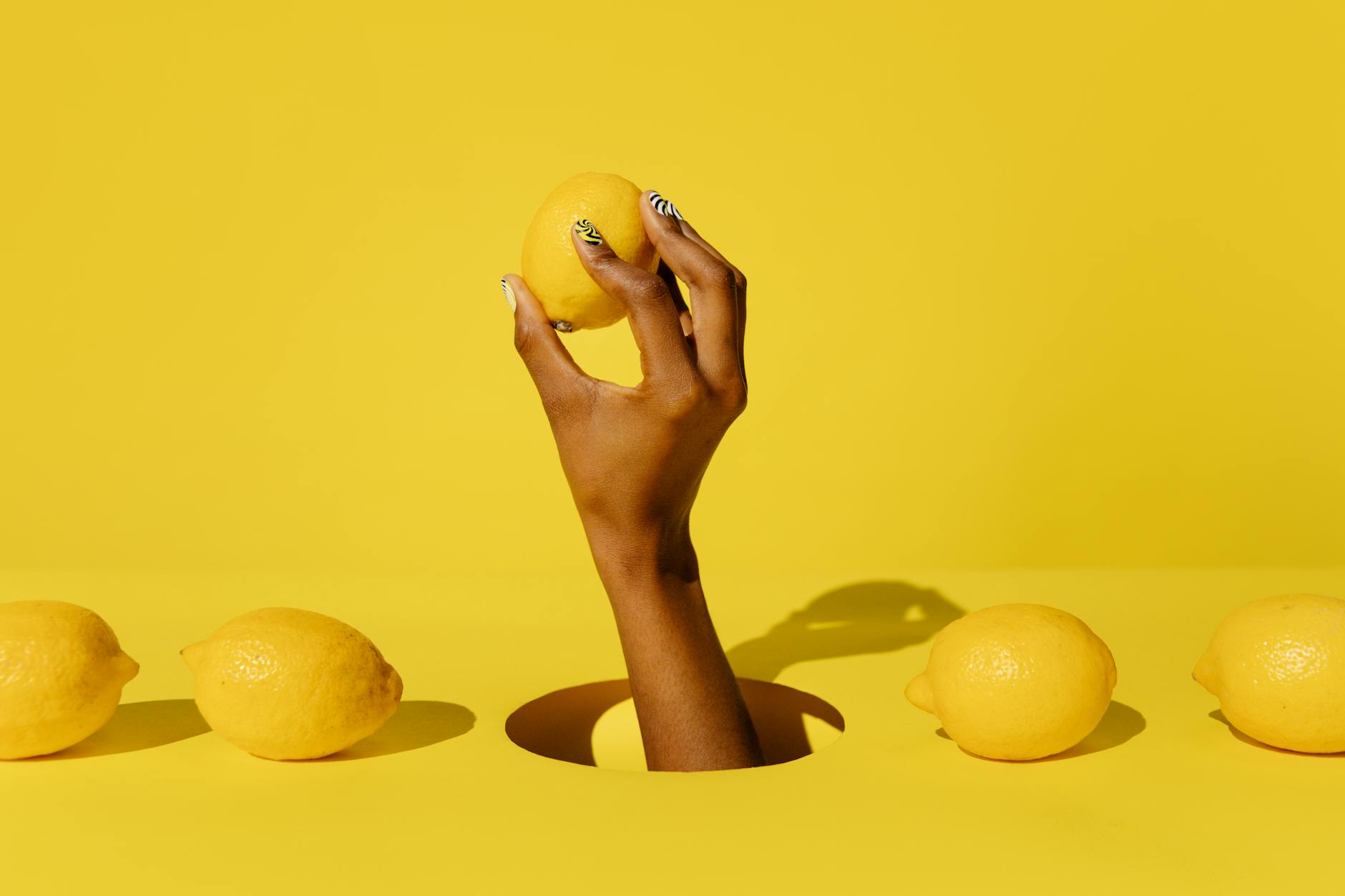 Une main tenant un citron contre un fond jaune éclatant, évoquant la fraîcheur et la vitalité