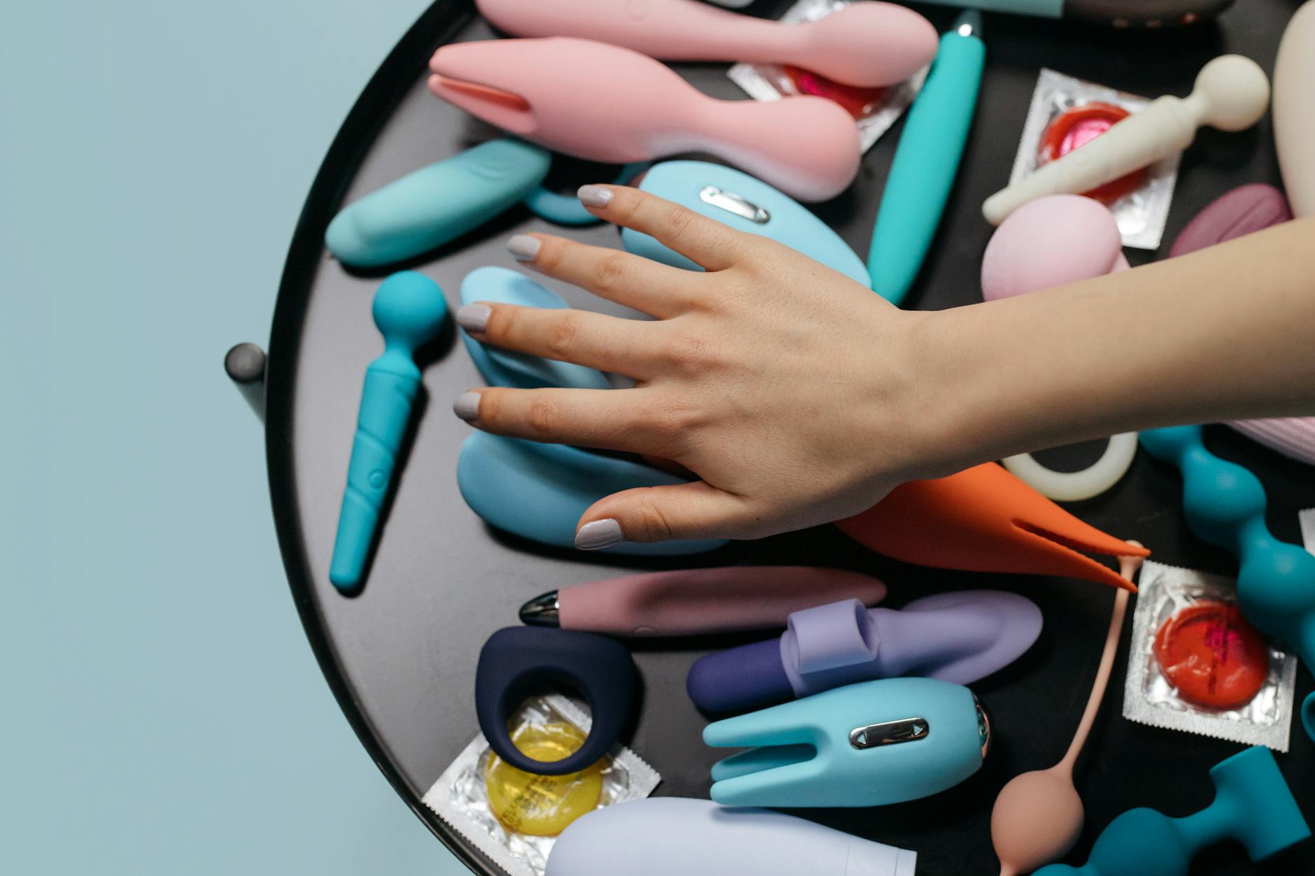 Hands reaching toward a collection of colorful vibrators, representing openness and choice in couples play