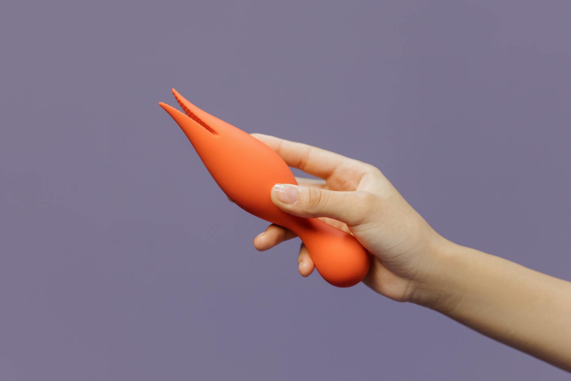 A close-up of a hand holding a vibrator, representing self-pleasure and intimacy during long-distance relationships