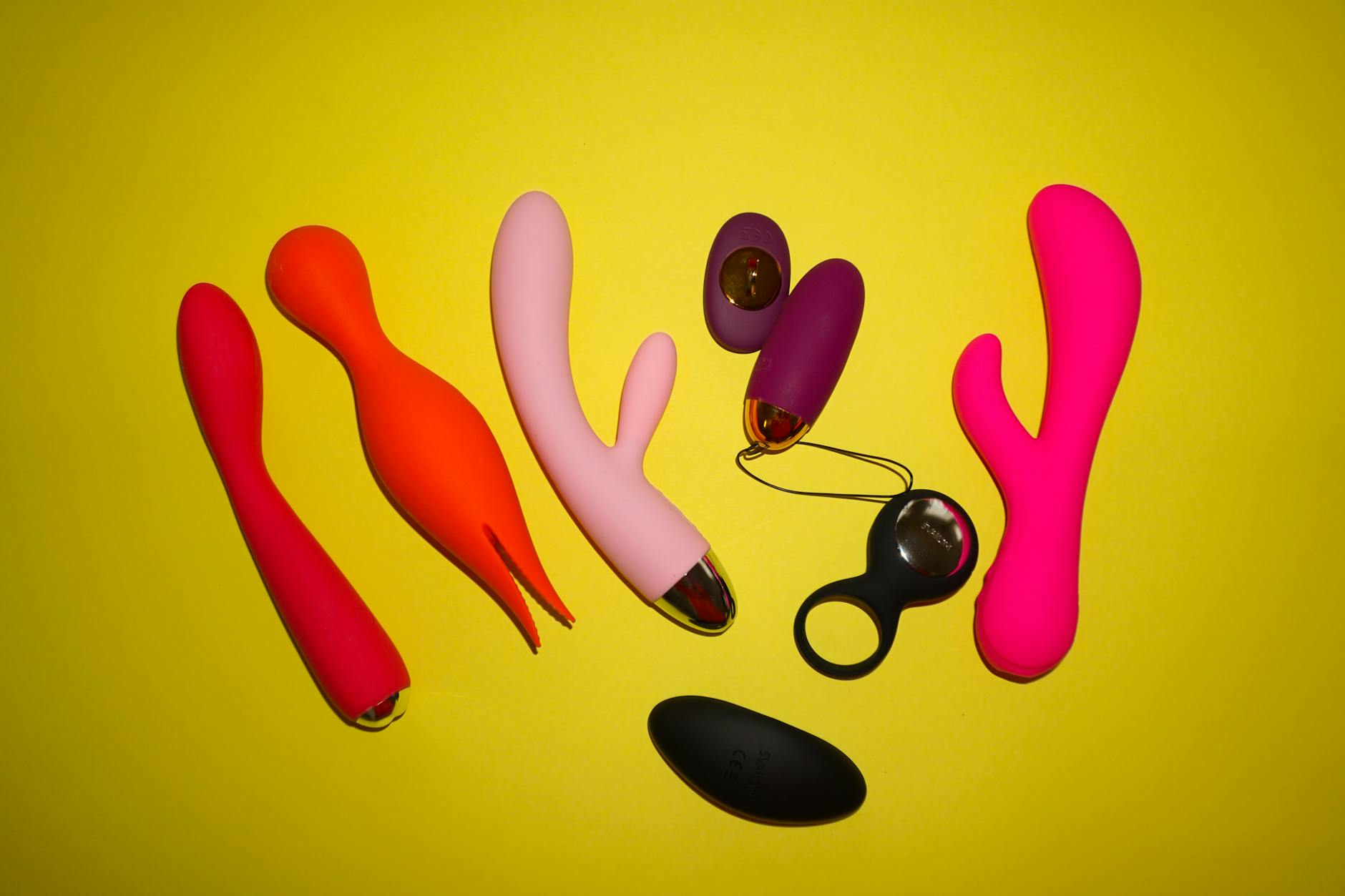 Vibrateurs colorés stylisés sur fond jaune vif, mettant en avant des formes et designs variés