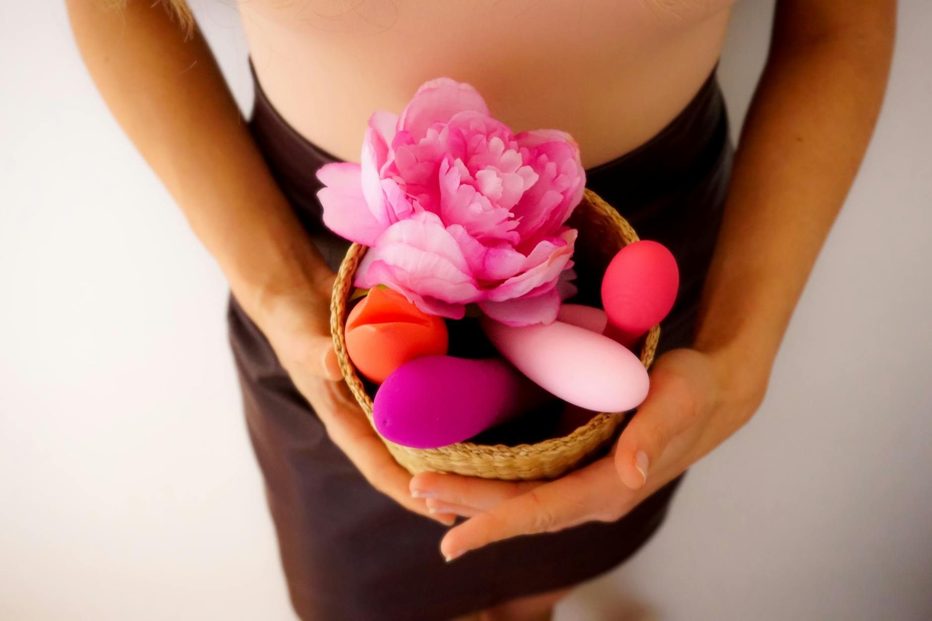 Hand reaching over a collection of colorful vibrators including lemon clitoral stimulators arranged on a surface